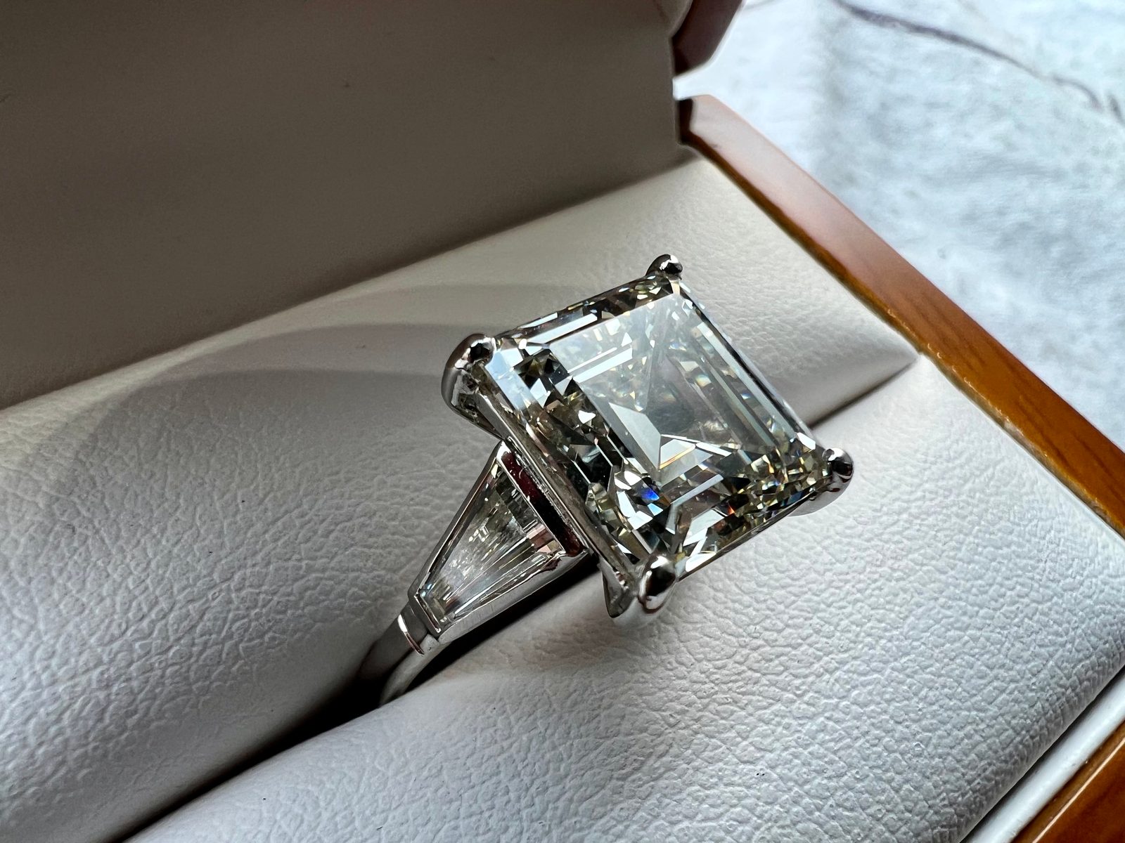 Emerald-cut centre with tapered baguette shoulders, platinum mount.