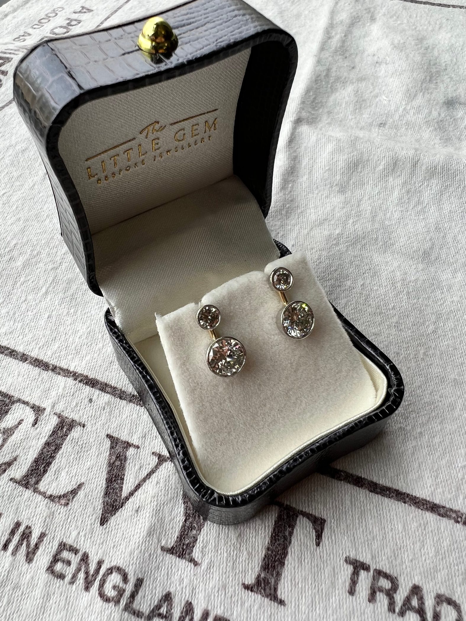 The Little Gem bespoke jewellery: a brand-embossed crocodile-leather ring box, diamond earrings on the cream interior, photographed against a velvet jeweller's cloth.